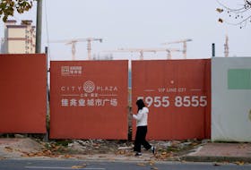 A woman walks past a construction site of Kaisa Group Holdings, in Shanghai, China, December 7, 2021.