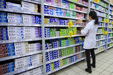 A salesperson arranges toothpaste products on a shelf at a supermarket in Shanghai, China, March 10, 2016.
