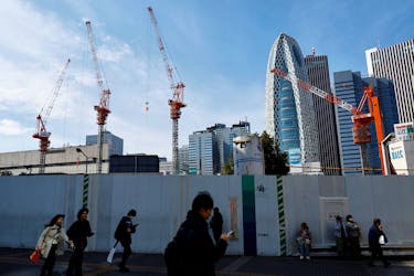 Passersby walk in front of a construction site in Tokyo, Japan February 15, 2024. 