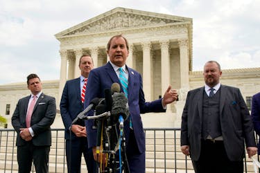 Texas Attorney General Ken Paxton, flanked by Missouri Attorney General Eric Schmitt and Texas Solicitor General Judd Stone, speaks during a news conference after the U.S. Supreme Court heard oral arguments in President Joe Biden's bid to rescind a Trump-era immigration policy that forced migrants to stay in Mexico to await U.S. hearings on their asylum claims, in Washington, U.S., April 26, 2022.