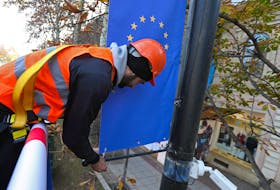 Worker Goga Akhvlediani hangs a banner with a European Union flag on a street in Tbilisi, Georgia December 15, 2023.