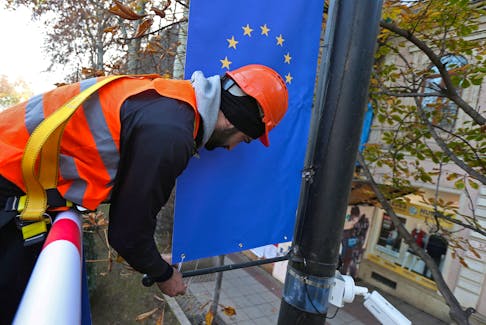 Worker Goga Akhvlediani hangs a banner with a European Union flag on a street in Tbilisi, Georgia December 15, 2023.