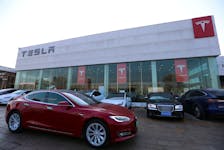 A Tesla car is driven past a store of the electric vehicle (EV) maker in Beijing, China January 4, 2024.