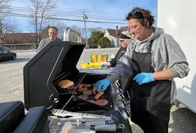 Sisters Laura Ross (from right) and Dorothy Penney were the grill masters for the free barbecue at the Barrington Care and Recovery Centre on April 23. Barrington Municipal Warden Eddie Nickerson stands nearby, enjoying a cheeseburger. Kathy Johnson