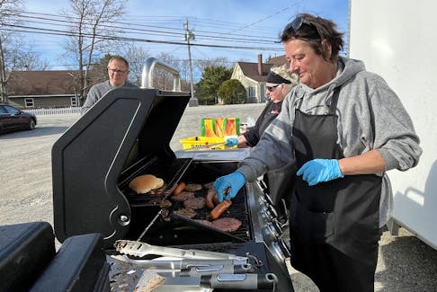 Sisters Laura Ross (from right) and Dorothy Penney were the grill masters for the free barbecue at the Barrington Care and Recovery Centre on April 23. Barrington Municipal Warden Eddie Nickerson stands nearby, enjoying a cheeseburger. Kathy Johnson