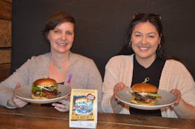 Danya O’Malley, left, executive director of P.E.I. Family Violence Prevention Services, and Emily Anne Fullerton, development co-ordinator for the organization, prepare to chow down on their "Gettin' Diggy Wit It' burgers as part of P.E.I. Burger Love at Lone Oak Brewpub in Charlottetown on April 3. Dave Stewart • The Guardian