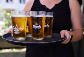 A bar worker carries a tray of Carlsberg beer in Copenhagen, Denmark, July 30, 2022.