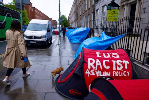 A woman walks past a tent belonging to an asylum seeker outside the International Protection Office (IPO), where hundreds of migrants in search of accommodation have been sleeping on the streets for several months with more arriving every day, in Dublin, Ireland, April 30, 2024. Ireland's government has said it plans to introduce emergency legislation to resume sending migrants back to Britain.