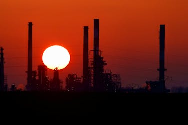 The sun sets behind the chimneys of the Total Grandpuits oil refinery, southeast of Paris, France, March 1, 2021. 