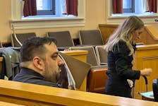 Chris Carter uses a notebook to shield his face from a reporter's camera in Newfoundland and Labrador Supreme Court Tuesday, April 30. At right is prosecutor Ashley Targett. TARA BRADBURY • THE TELEGRAM