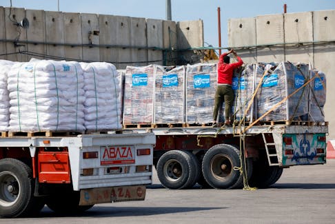 A driver adjusts a rope as he stands on a truck carrying humanitarian aid bound for the Gaza Strip, at the Kerem Shalom crossing, amid the ongoing conflict between Israel and the Palestinian Islamist group Hamas, in southern Israel, March 14, 2024.