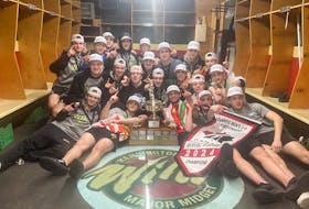 The Kensington Monaghan Farms Wild gather around the team logo in their dressing room for a photo with the Atlantic major under-18 male hockey championship trophy and banner on April 7. The Wild had just returned to Credit Union Centre in Kensington from the regional championship in Lantz, N.S. Contributed