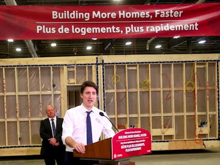Prime Minister Justin Trudeau standing under a banner reading "Building More Homes, Faster." 