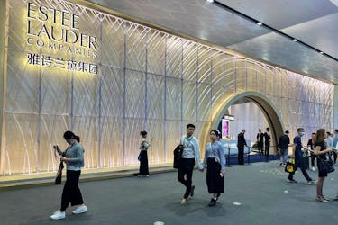 People walk past a booth of Estee Lauder at the third China International Consumer Products Expo, in Haikou, Hainan province, China April 12, 2023.