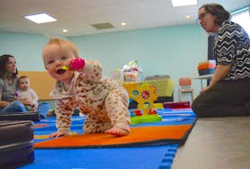 Eight-month-old Remi Taylor smiles as she crawls along the mats during Movers and Shakers Story Time at the James McConnell Memorial Library in Sydney on Wednesday. Also seen are Kendra MacIsaac, left, holding her 14-month-old daughter Grace MacIsaac and Cape Breton Regional Library program co-ordinator Tara MacNeil. Movers and Shakers is a drop-in program for babies, tots, preschoolers and their parents, grandparents and caregivers to enjoy songs, stories, rhymes and play with library staff. The next Movers and Shakers takes place May 16 and May 28 at the James McConnell Memorial Library from 10:30-11:30 a.m. Christopher Connors/Cape Breton Post
