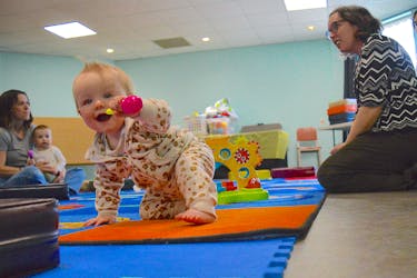 Eight-month-old Remi Taylor smiles as she crawls along the mats during Movers and Shakers Story Time at the James McConnell Memorial Library in Sydney on Wednesday. Also seen are Kendra MacIsaac, left, holding her 14-month-old daughter Grace MacIsaac and Cape Breton Regional Library program co-ordinator Tara MacNeil. Movers and Shakers is a drop-in program for babies, tots, preschoolers and their parents, grandparents and caregivers to enjoy songs, stories, rhymes and play with library staff. The next Movers and Shakers takes place May 16 and May 28 at the James McConnell Memorial Library from 10:30-11:30 a.m. Christopher Connors/Cape Breton Post