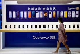 A woman walks past a counter displaying mobile phones at the Qualcomm booth during the 2021 China International Fair for Trade in Services (CIFTIS) in Beijing, China September 4, 2021.