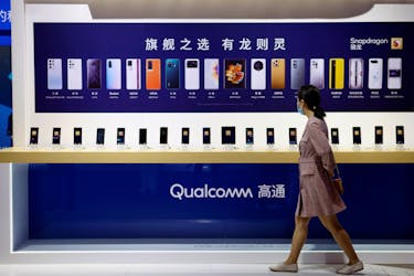 A woman walks past a counter displaying mobile phones at the Qualcomm booth during the 2021 China International Fair for Trade in Services (CIFTIS) in Beijing, China September 4, 2021.