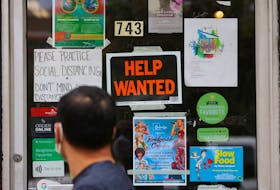 A pedestrian passes a "Help Wanted" sign in the door of a hardware store in Cambridge, Massachusetts, U.S., July 8, 2022.  