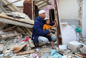 A wounded Palestinian man, carrying his injured son, reacts at the site of an Israeli strike on a house, amid the ongoing conflict between Israel and the Palestinian Islamist group Hamas, in Rafah, in the southern Gaza Strip, May 1, 2024.