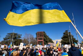 A Ukrainian flag is waved during an anti-war protest, after Russia launched a massive military operation against Ukraine, in front of the United Nations Office in Geneva, Switzerland, February 26, 2022.