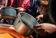 Palestinians gather to receive food cooked by a charity kitchen, amid shortages of aid supplies, after Israeli forces launched a ground and air operation in the eastern part of Rafah, as the ongoing conflict between Israel and Hamas continues, in Rafah, in the southern Gaza Strip May 8, 2024.