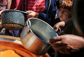 Palestinians gather to receive food cooked by a charity kitchen, amid shortages of aid supplies, after Israeli forces launched a ground and air operation in the eastern part of Rafah, as the ongoing conflict between Israel and Hamas continues, in Rafah, in the southern Gaza Strip May 8, 2024.