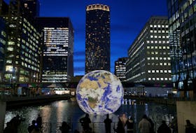 People look at Luke Jerram's 'Floating Earth', an installation as part of the Canary Wharf Winter Lights festival in the financial district in London, Britain, January 17, 2023.