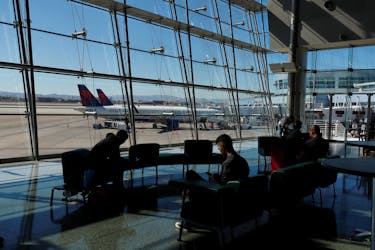 Travelers sit in a lounge area as Delta Air Lines plane park at a gate in McCarran International Airport in Las Vegas, Nevada, U.S., February 14, 2020. Picture taken February 14, 2020. 