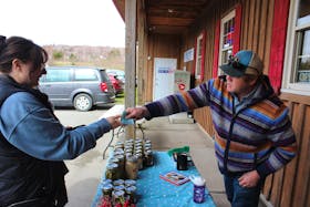 Mark Jantunen of  Bull & Tree Farm hands change to a customer at a Cape Breton Farmers' Market pop-up shop at the Pan Cape Breton Food Hub Co-op building in Bras d'Or on Saturday. Jantunen was one of a handful of market vendors to open at the shop after the regular location in Sydney was closed by the landlords amid a dispute with the market over missed payments. LUKE DYMENT/CAPE BRETON POST