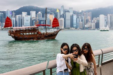Tourists take photos in front of Victoria Harbour, in Tsim Sha Tsui, in Hong Kong, China April 29, 2024.