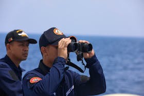A Philippine Coast Guard personnel looks through a binocular while conducting a resupply mission for Filipino troops stationed at a grounded warship in the South China Sea, October 4, 2023.