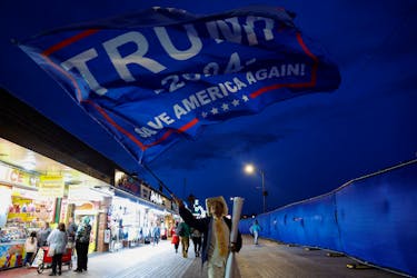 T Tran, a supporter of former U.S. President and Republican presidential candidate Donald Trump from California, waves a Trump 2024 flag on a boardwalk following a campaign rally held by Trump in Wildwood, New Jersey, U.S., May 11, 2024.
