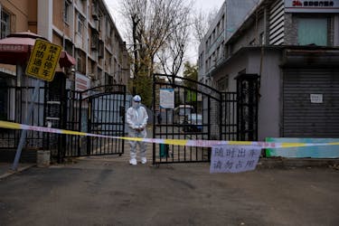 An epidemic-prevention worker in a protective suit stands guard at the gate of a residential compound as coronavirus disease (COVID-19) outbreaks continue in Beijing, China November 28, 2022.