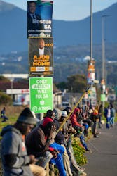 Unemployed job seekers line a street waiting for casual employment, as they sit beneath election campaign posters for the South African general elections which will be held on May 29, in Cape Town, South Africa, April 19, 2024. 