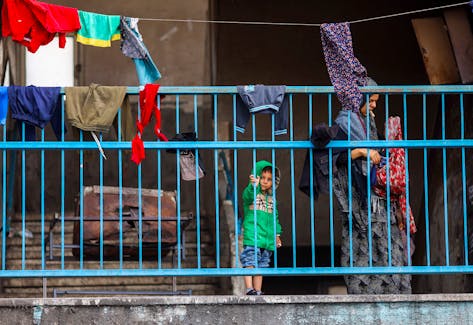 Palestinians stand behind the railings at a nearly deserted school used as a shelter by displaced people who fled Rafah after Israeli forces launched a ground and air operation in the eastern part of the southern Gaza City, amid the ongoing conflict between Israel and Hamas, in Rafah, in the southern Gaza Strip May 13, 2024.