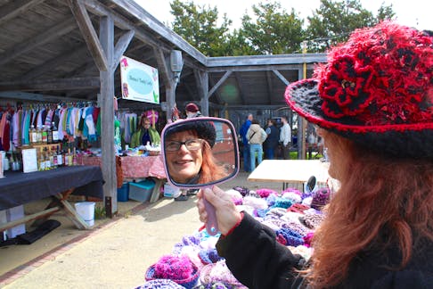 Clementsport’s Carolynn Price checks out one of her homemade hats May 11 at the Annapolis Royal Farmers and Traders Market. She had a table full of handmade hats for sale that included wide-brimmed Greta Garbo hats, short-brimmed flappers, fishermen, poor boy and baseball caps.