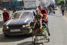 A displaced Palestinian man, who fled Jabalia after the Israeli military called on residents to evacuate, pushes children in a trolley as they make their way towards Gaza City, amid the ongoing conflict between Israel and Hamas, May 12, 2024.