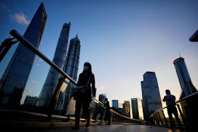 People walk on an overpass past office towers in the Lujiazui financial district of Shanghai, China October 17, 2022.
