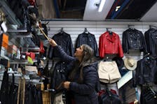 A woman cleans with a duster at a clothing store, as Argentina is battling inflation that is running on an annual basis above 275%, in Buenos Aires, Argentina, April 11, 2024.