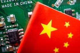 A Chinese flag is displayed next to a "Made in China" sign seen on a printed circuit board with semiconductor chips, in this illustration picture taken February 17, 2023.