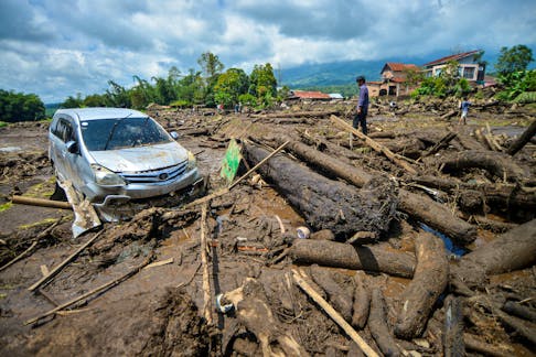 A man stands near a damaged car in an area affected by heavy rain brought flash floods and landslides in Agam, West Sumatra province, Indonesia, May 12, 2024, in this photo taken by Antara Foto. Antara Foto/Iggo El Fitra/via REUTERS