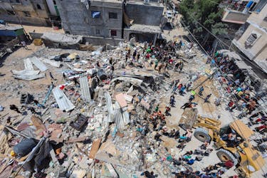 Palestinians gather as rescuers search for casualties trapped under the rubble of of a house hit in an Israeli strike, amid the ongoing conflict between Israel and the Palestinian Islamist group Hamas, in Nuseirat refugee camp in the central Gaza Strip, May 14, 2024.
