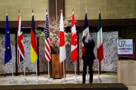 An official adjusts the flags before G7 foreign ministers gather for a family photo during their meetings in Tokyo, Japan, November 8, 2023.