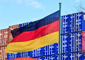 A German flag blows in the wind in front of a stack of containers at the harbour in Hamburg, Germany, February 24, 2022.