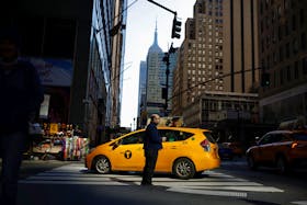 A man stands on the street as a taxi passes in Manhattan, in New York City, U.S., March 20, 2023.