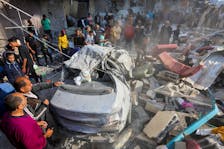 Palestinians gather near the remains of a car at the site of an Israeli strike on a house, amid the ongoing conflict between Israel and the Palestinian Islamist group Hamas, in Nuseirat refugee camp in the central Gaza Strip, May 14, 2024.