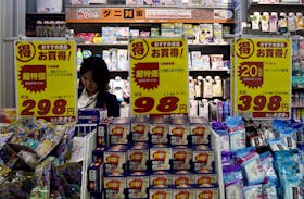 FILE PHOTO : A shopper is seen between price boards at a drug store in Tokyo, Japan, May 28, 2015.