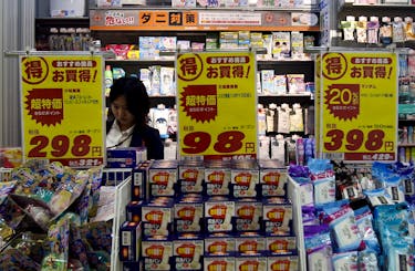 FILE PHOTO : A shopper is seen between price boards at a drug store in Tokyo, Japan, May 28, 2015.