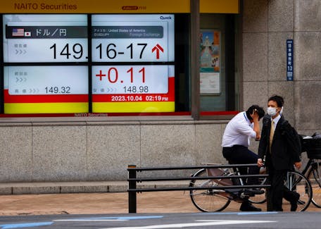 Passersby walk past an electric monitor displaying the Japanese yen exchange rate against the U.S. dollar outside a brokerage in Tokyo, Japan October 4, 2023.